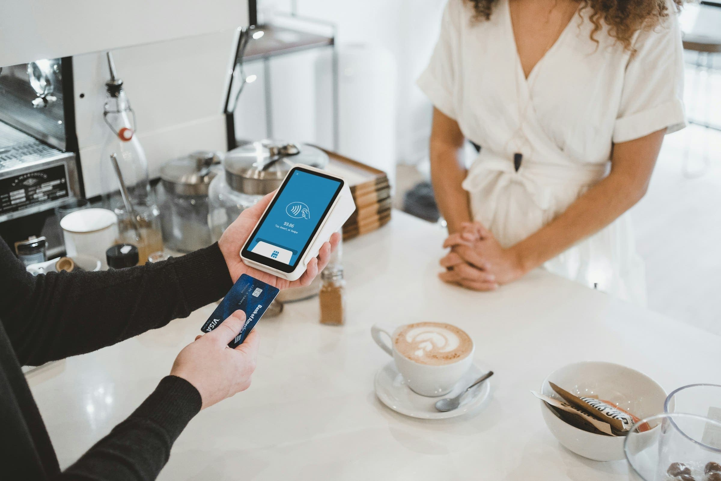 Customer inserts a bank card into a handheld payment terminal at a café counter